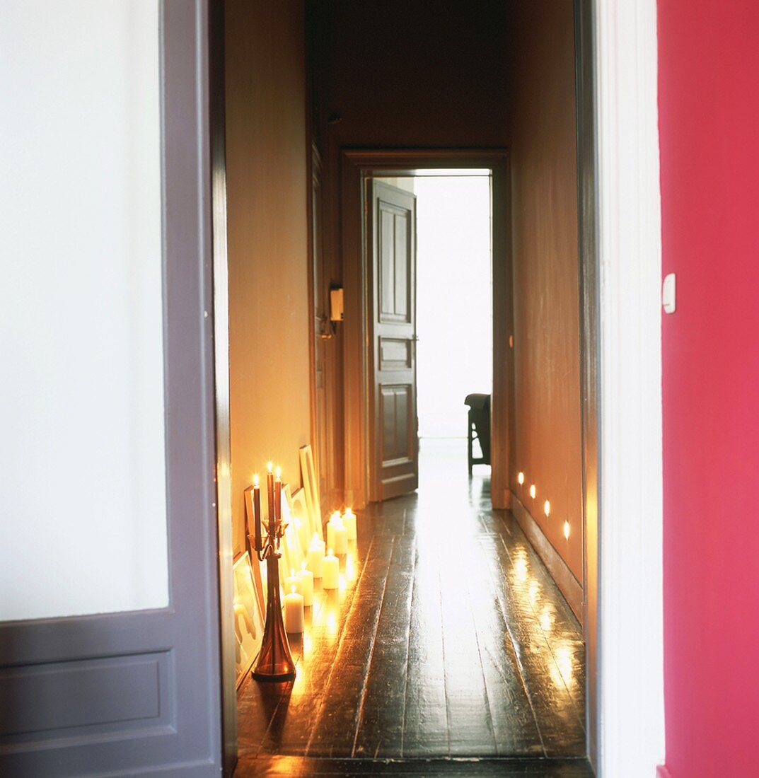 Blick durch geöffnete Türen in Flur mit brennende Kerzen auf dem Boden