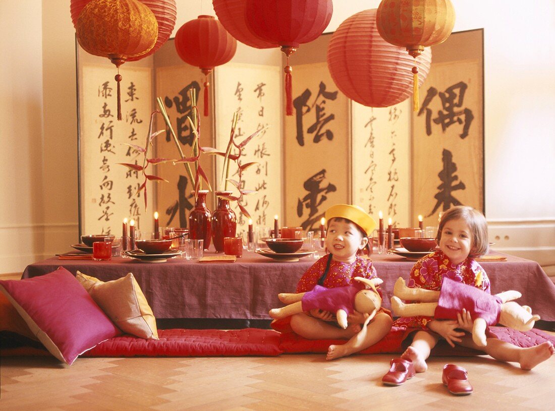 Zwei Mädchen spielen vor asiatisch gedecktem Tisch