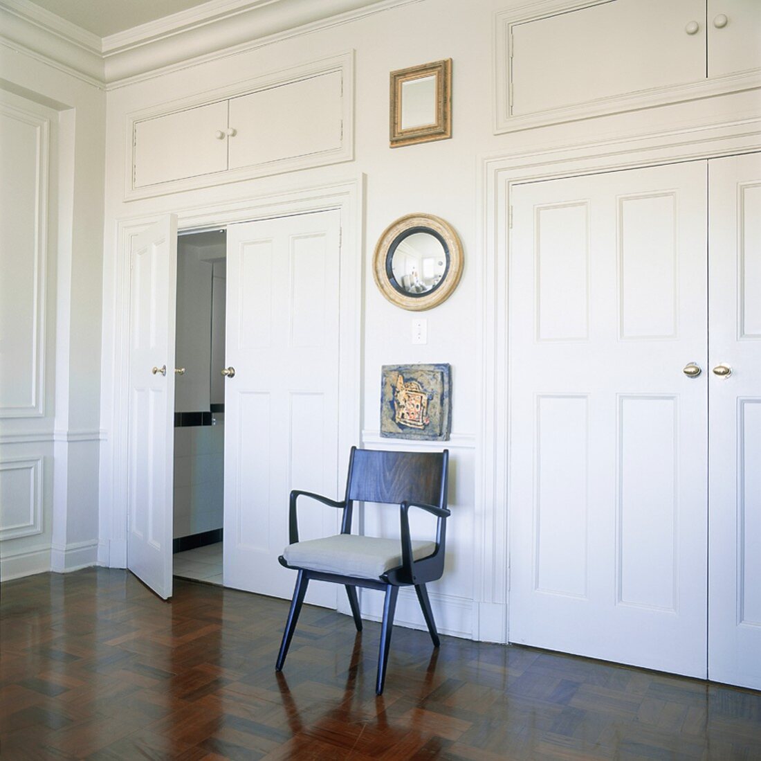 Designerstuhl in einem weißen Raum mit Flügeltüren und stuckierter Decke