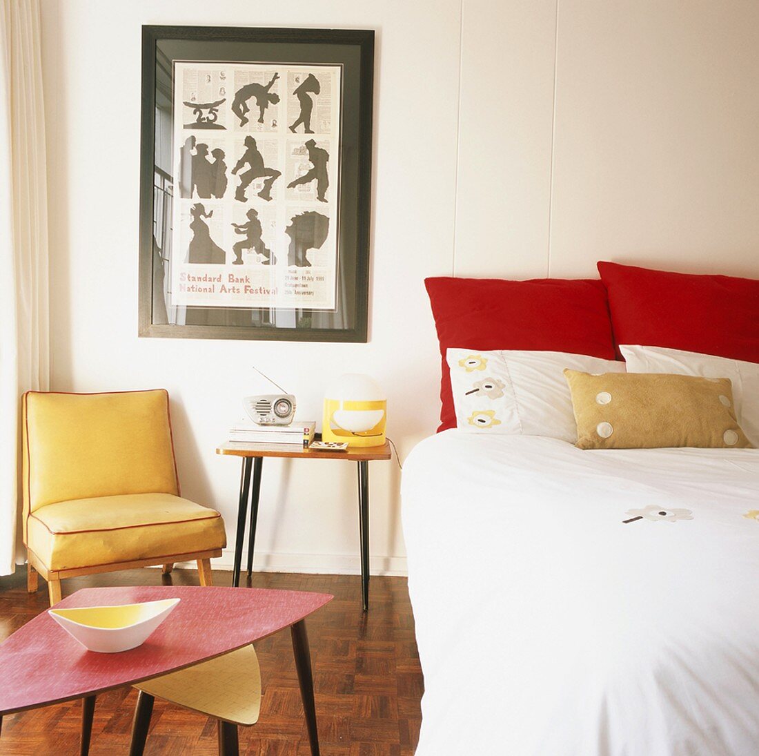 Farbenfrohes Retroschlafzimmer mit großem Bett, 50er Jahre Beistelltisch, Loungesessel und Dreibeintischen