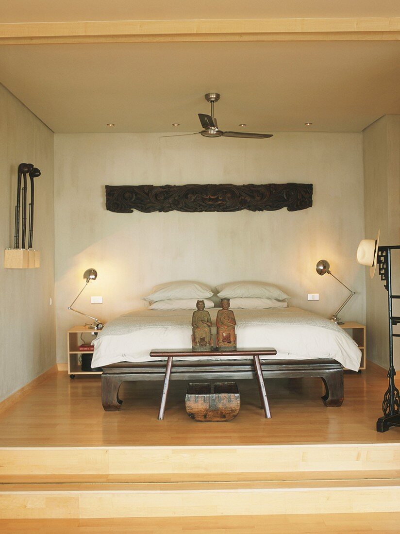 Erhöhte Schlafnische mit Bett und Dekoelementen im asiatischen Stil, gemixt mit moderner Elektronik