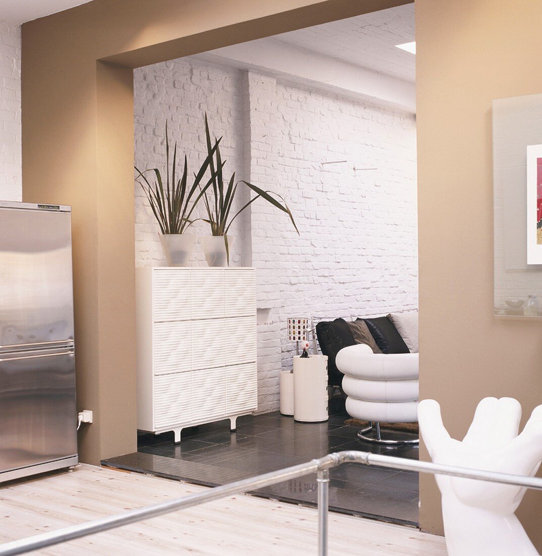 Blick in einen Wohnraum mit weiss gestrichener Backsteinwand und Designmöbeln