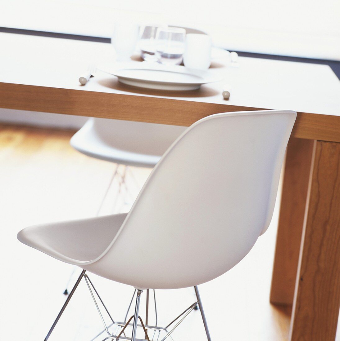 weiße Designerstühle an einem schlichten Holztisch