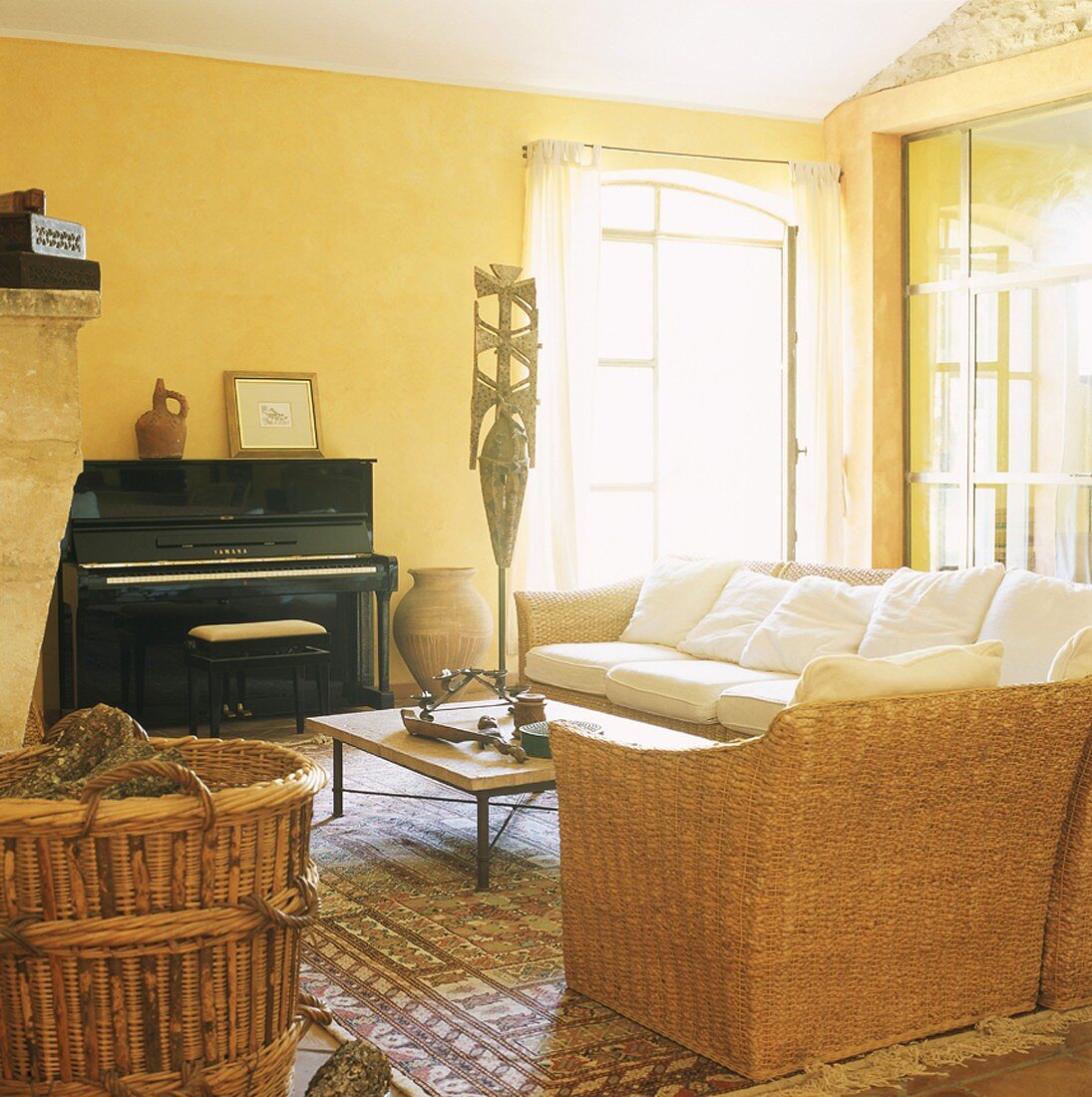 Schwarzes Klavier und Rattansitzmöbel in einem einladenden sonnengelben Raum mit schräger Decke