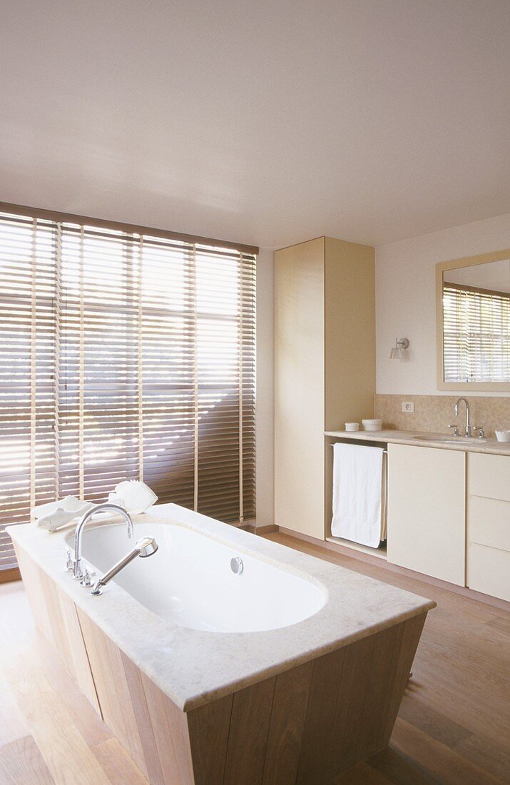 Freistehende Badewanne mit Holzvertäfelung in einem großzügigen Badezimmer mit raumhohen Fenstern