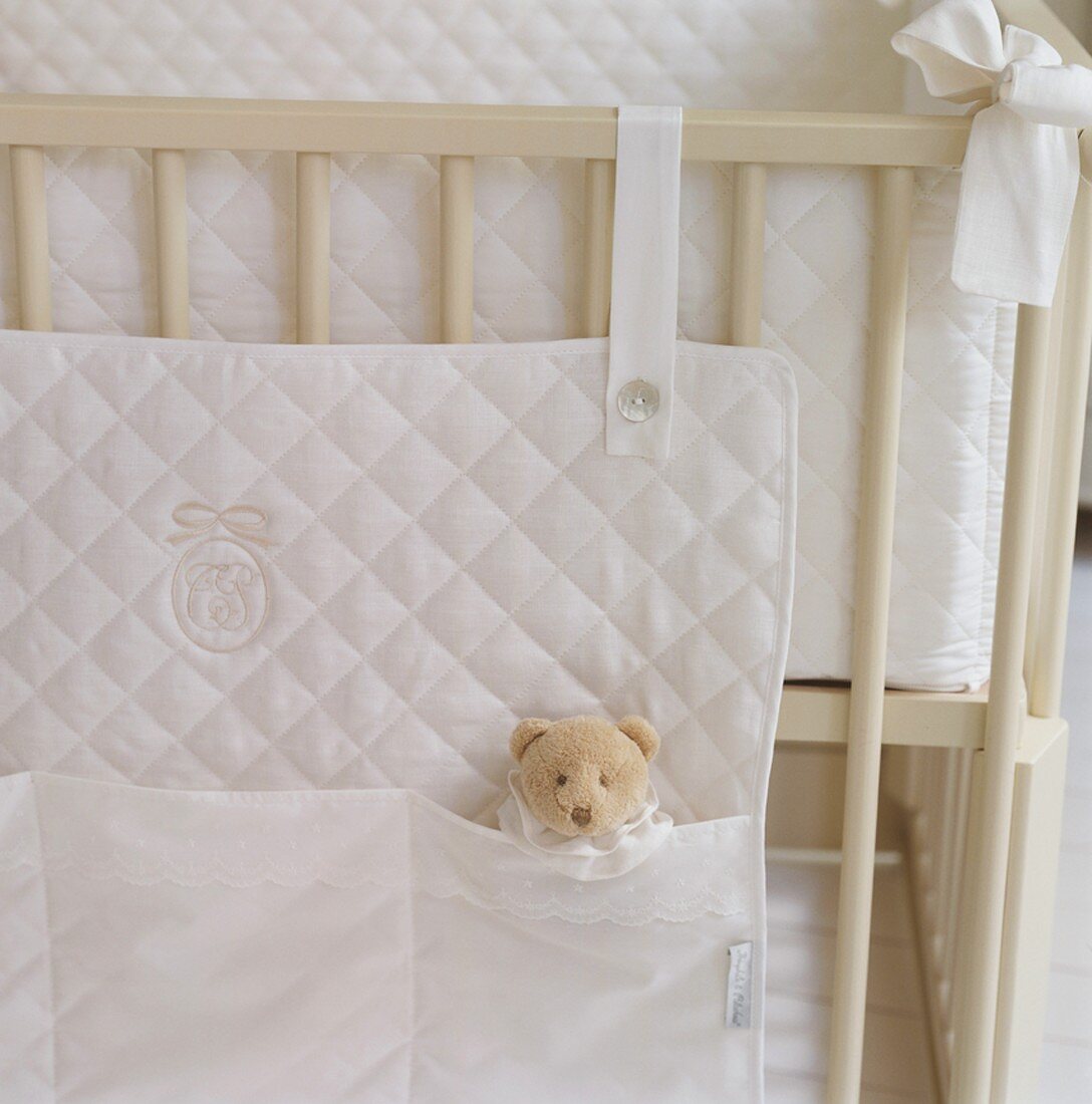 Die weiße Betttasche aus gestepptem Stoff schafft Ordnung an und im Kinderbettchen