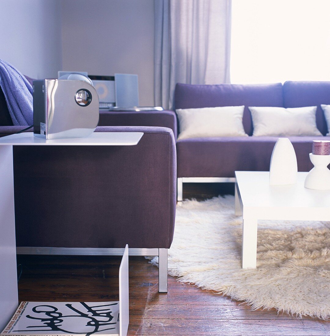 Moderne Sofas in Pflaume und ein großer Flokatiteppich schaffen eine entspannte Wohnzimmeratmosphäre
