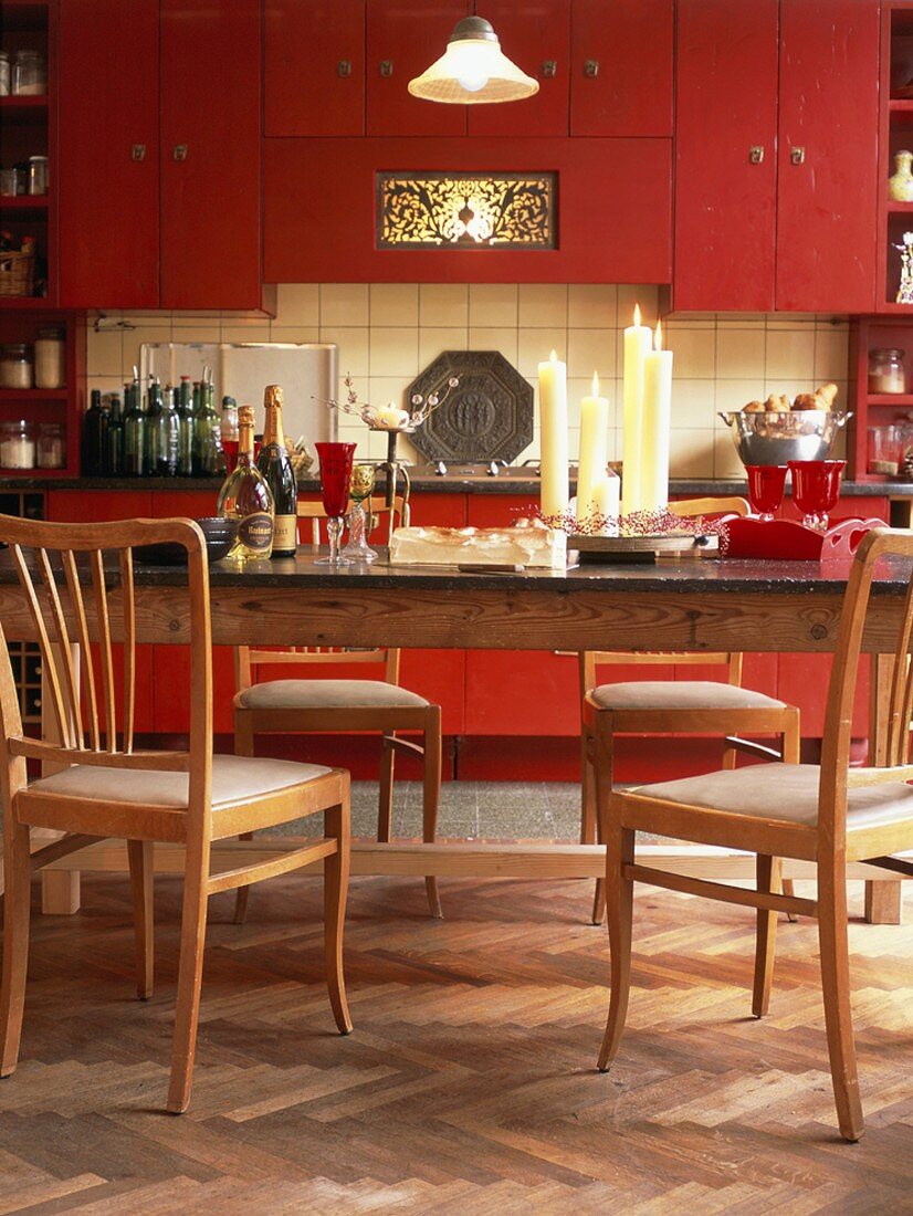 Eine gemütliche Wohnküche mit roten Schrankelementen und einem großen, alten Holztisch