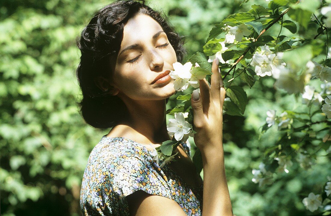 Frau riecht an duftenden Blütenzweigen