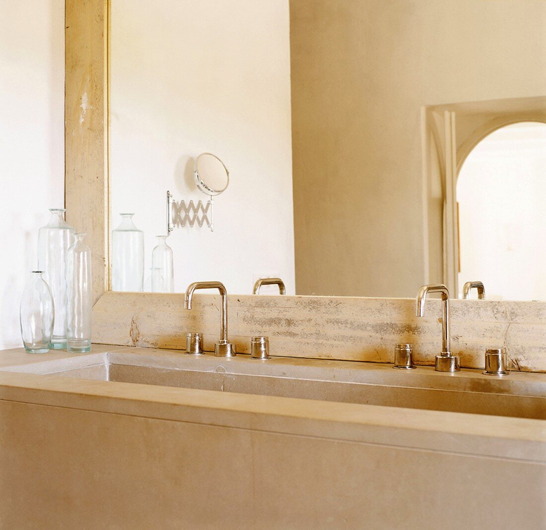 Ein riesiger Wandspiegel ist das Highlight des minimalistischen Natursteinbadezimmers