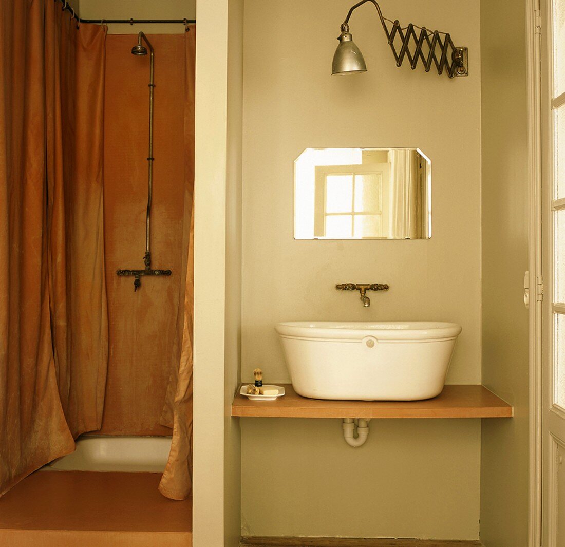 Ein Badezimmer mit einfacher Dusche und Waschtisch in einer Nische