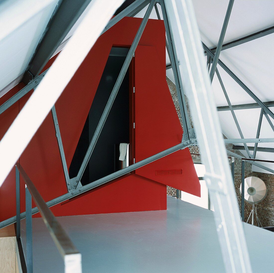 Roter Einbau zwischen Stahlträgern auf der Galerie eines Lofts mit Backsteinwänden