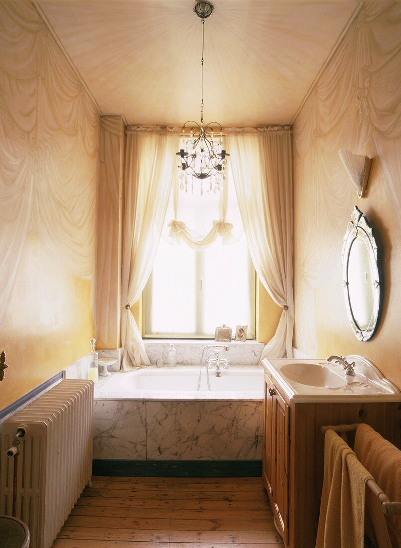 Prunkvoll und zugleich schlicht wirkt dieses Badezimmer mit Marmorbadewanne und aufgemalten Vorhängen