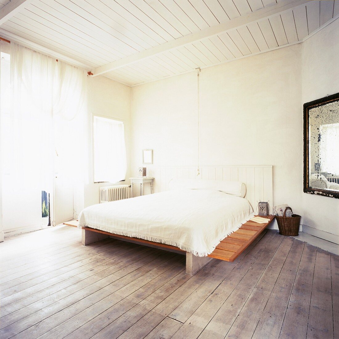 Das Bett in dem spartanisch eingerichteten Schlafzimmer vereint verschiedene Stile und Materialien zu einem Ganzen