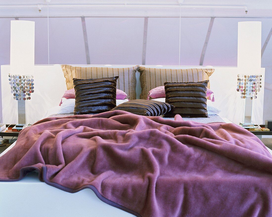 Ein gemütliches Doppelbett mit bunter Tagesdecke und zwei Nachttische mit Pailettenlampen