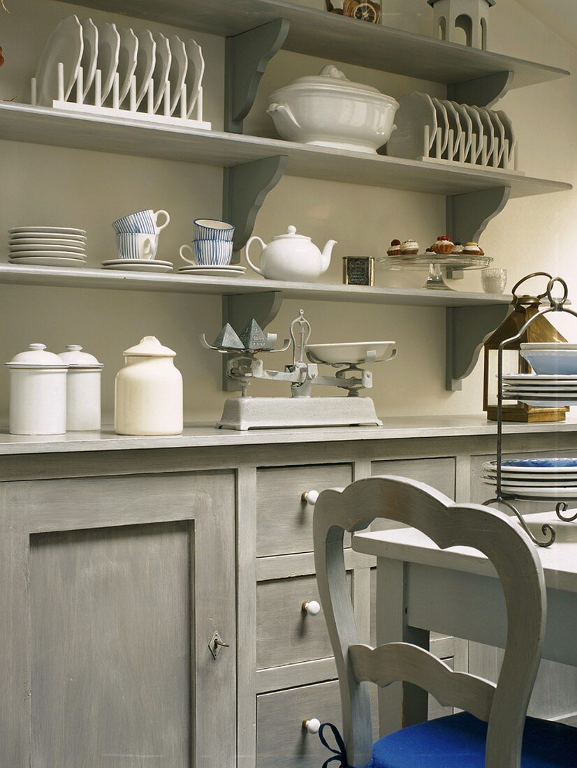 Küchenschrank und Wandboards mit Geschirr in einer romantischen Holzküche