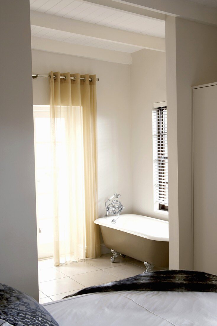 Blick vom Schlafzimmer in das angeschlossene, offene Badezimmer mit Clawfoot Badewanne