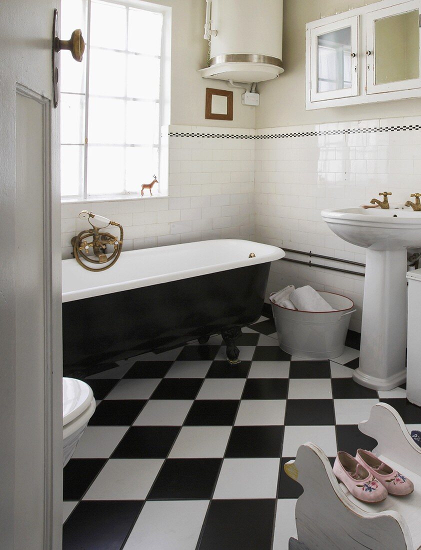 Eine schwarzweisse Clawfoot Badewanne und Schachbrettfliesen in einem alten, klassischen Badezimmer