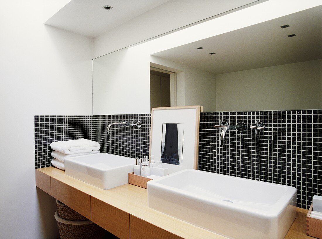 Schwarze Mosaikfliesen mit weissen Fugen bilden den Blickfang des modernen Badezimmers mit einem schlichten Waschtisch aus Holz
