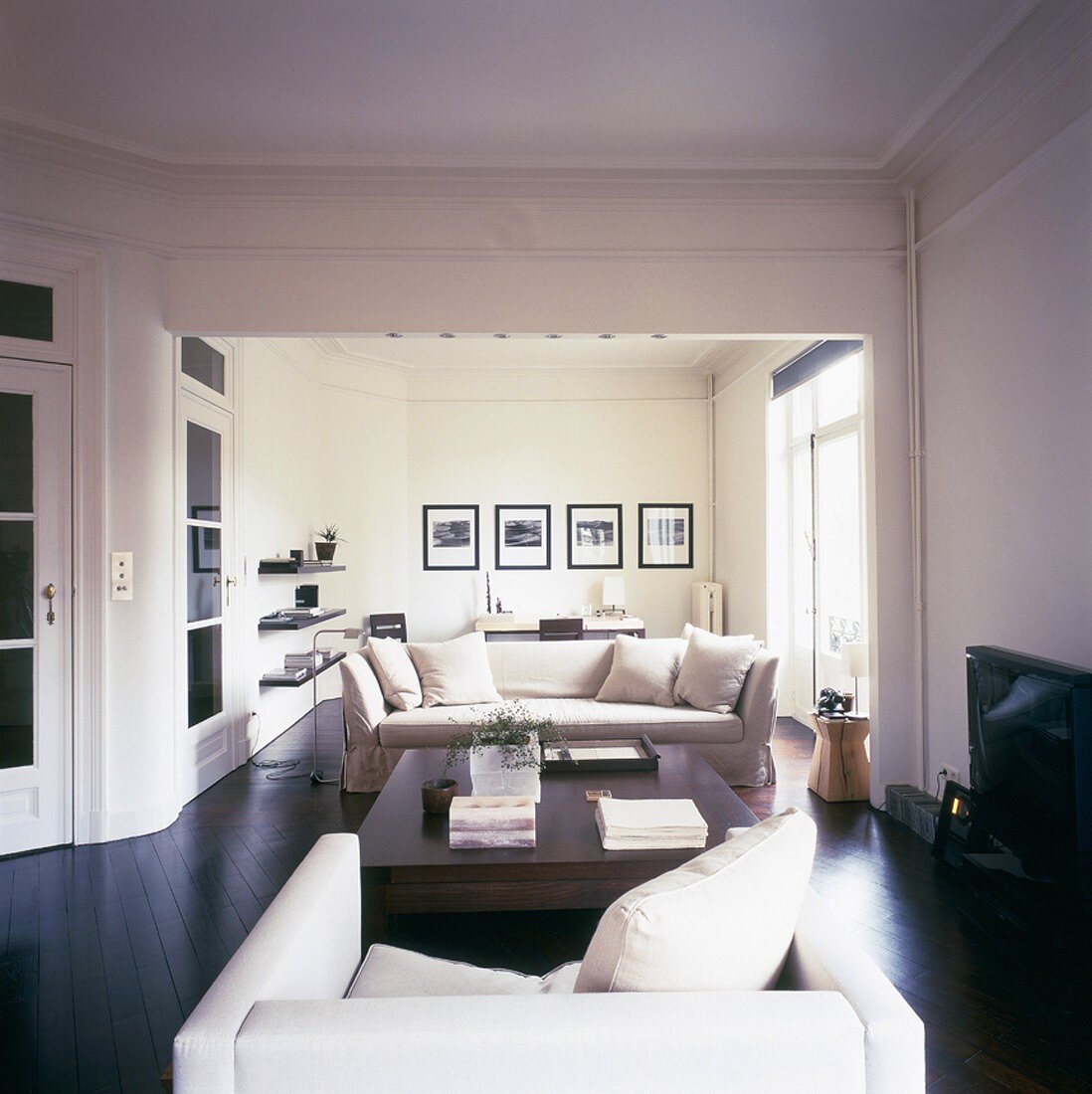 Blick in den stilvoll eingerichteten Wohnraum mit dunklem Parkettboden und Zierleisten an der Decke