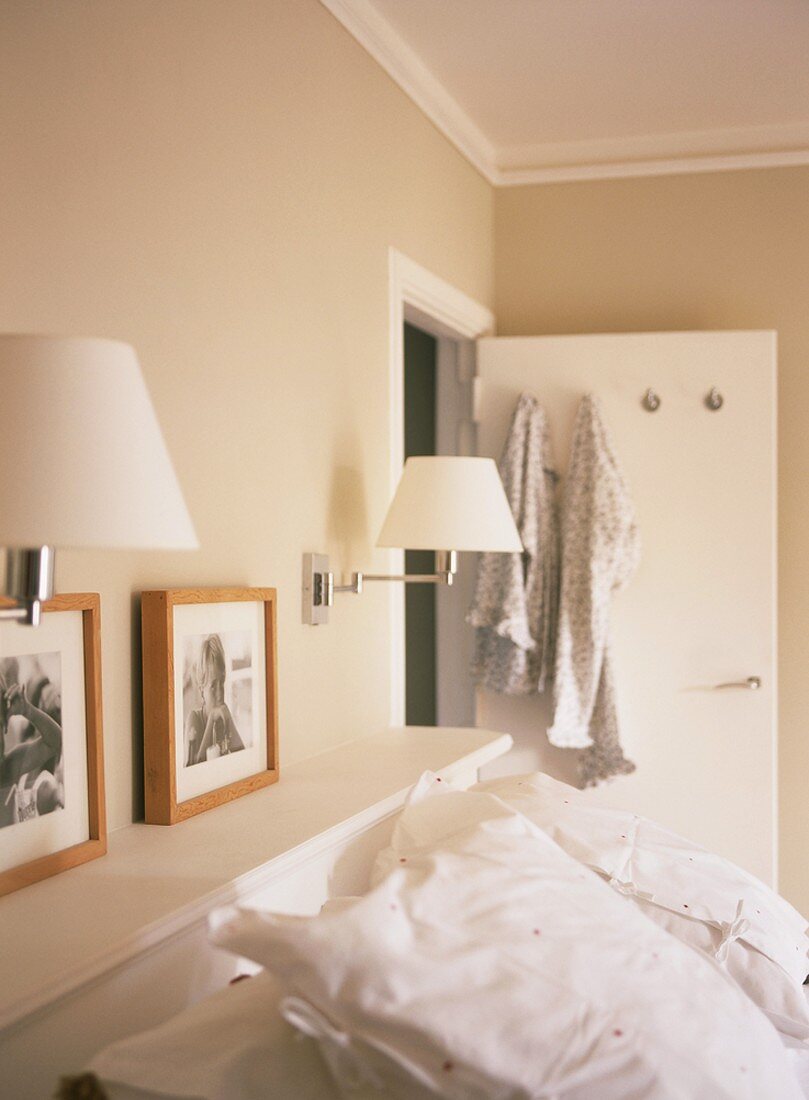 Moderne Wandleuchten und Fotos über dem Kopfteil eines Betts