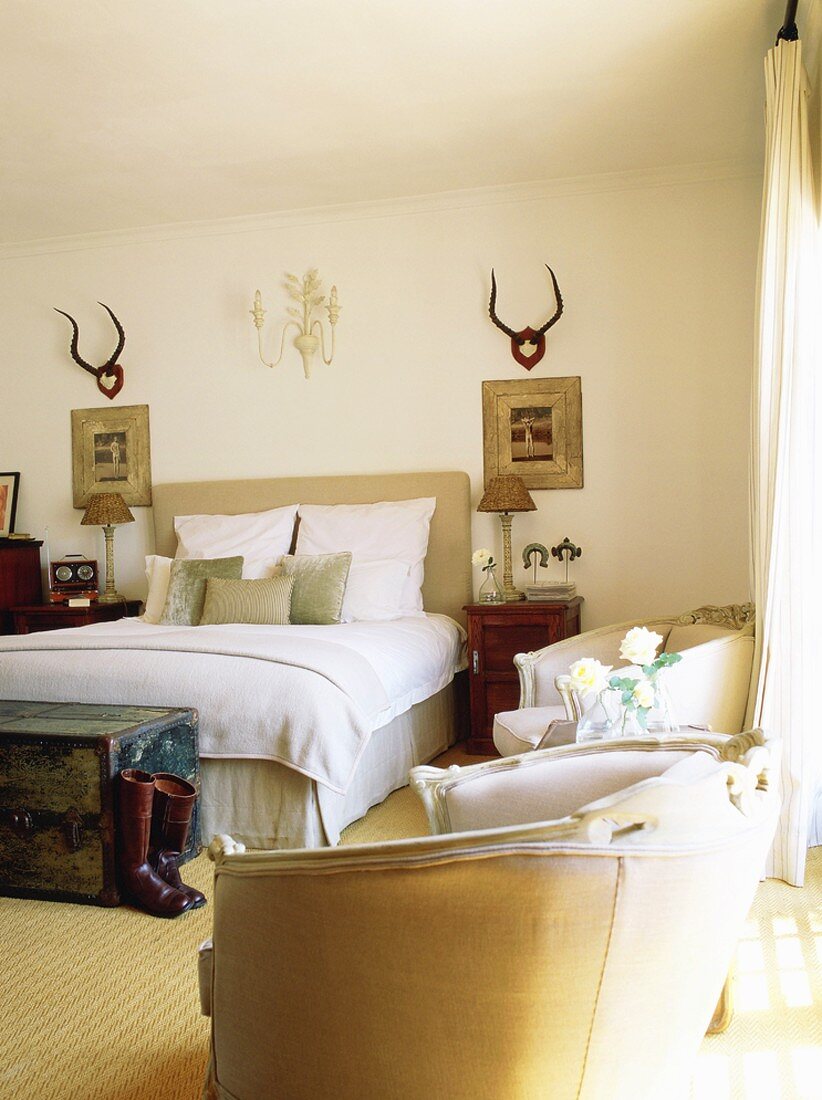 Elegante Antiksessel im Schlafzimmer mit grossem Doppelbett und rustikaler Landhausdeko