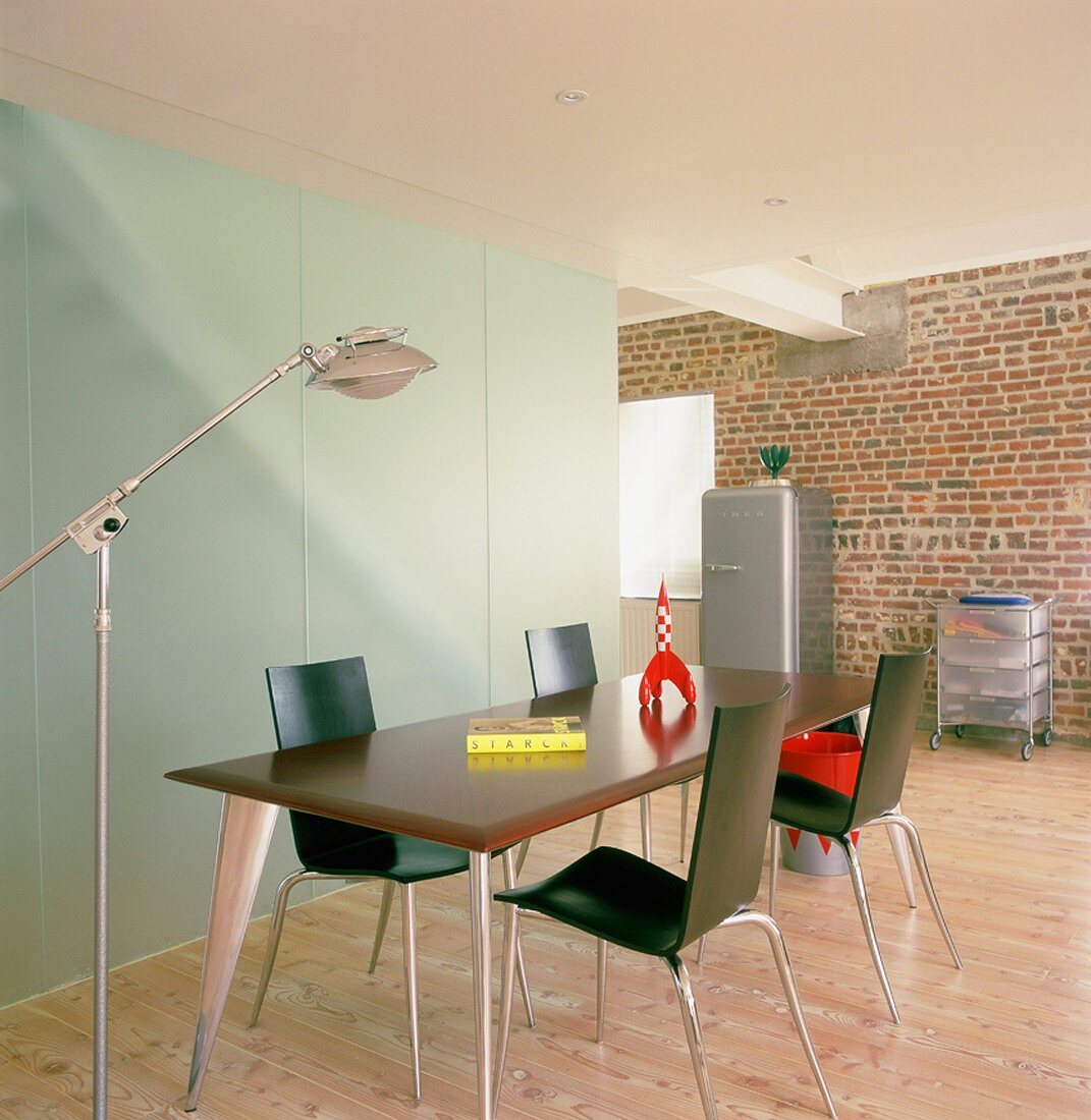 Eine stilvolle Esszimmergarnitur des Designers Philippe Starck in einem Raum mit Backsteinwand und einem Raumteiler aus Milchglas
