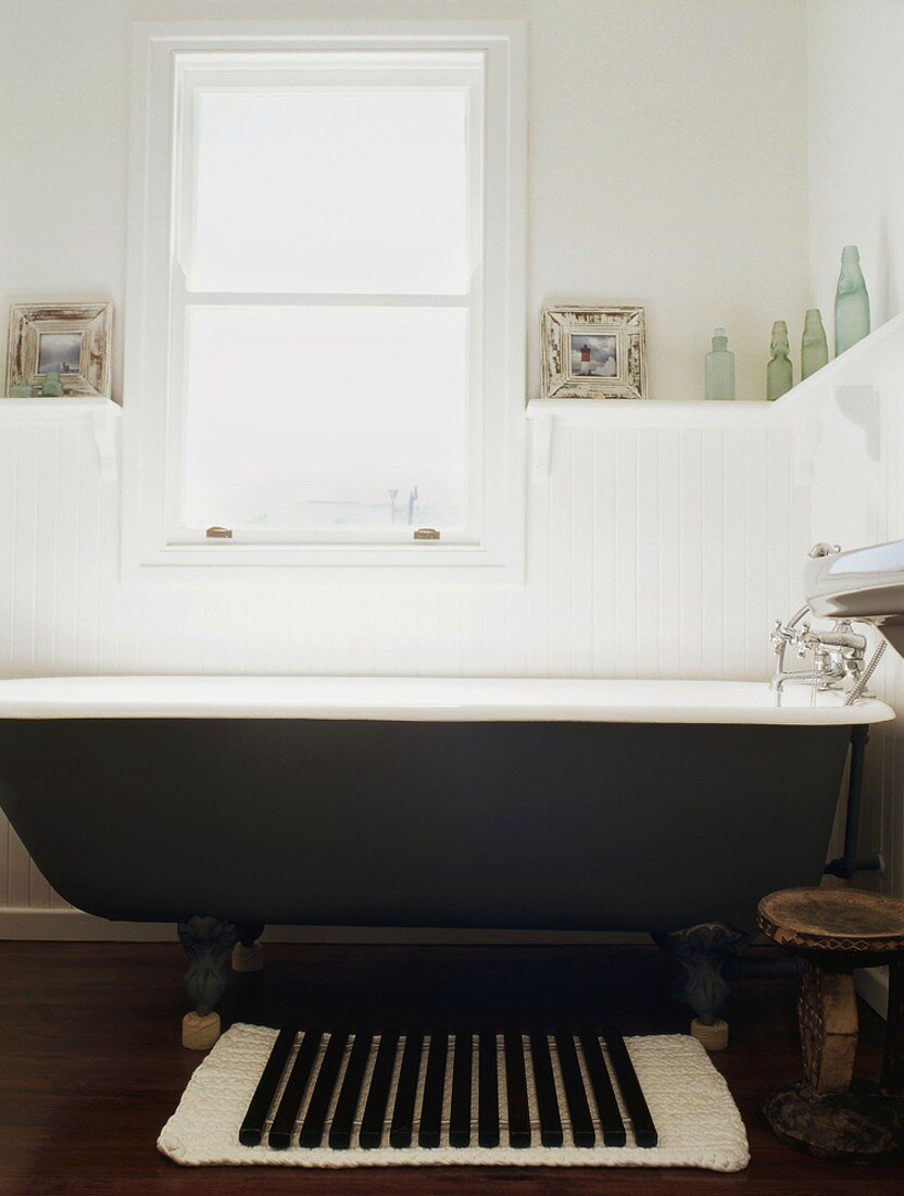 Eine Clawfoot Badewanne mit schwarzer Aussenbeschichtung ist der Blickfang des dezent dekorierten Badezimmers