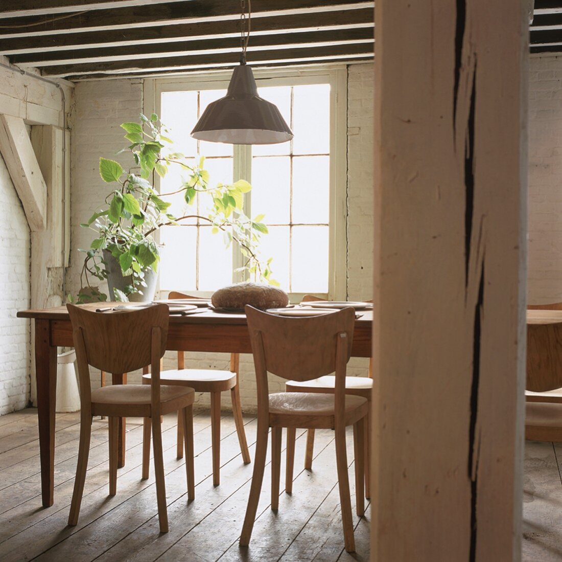 Einfache Holzmöbel bilden den Essplatz in einem traditionellen Fachwerkhaus mit typischer Holzbalkendecke