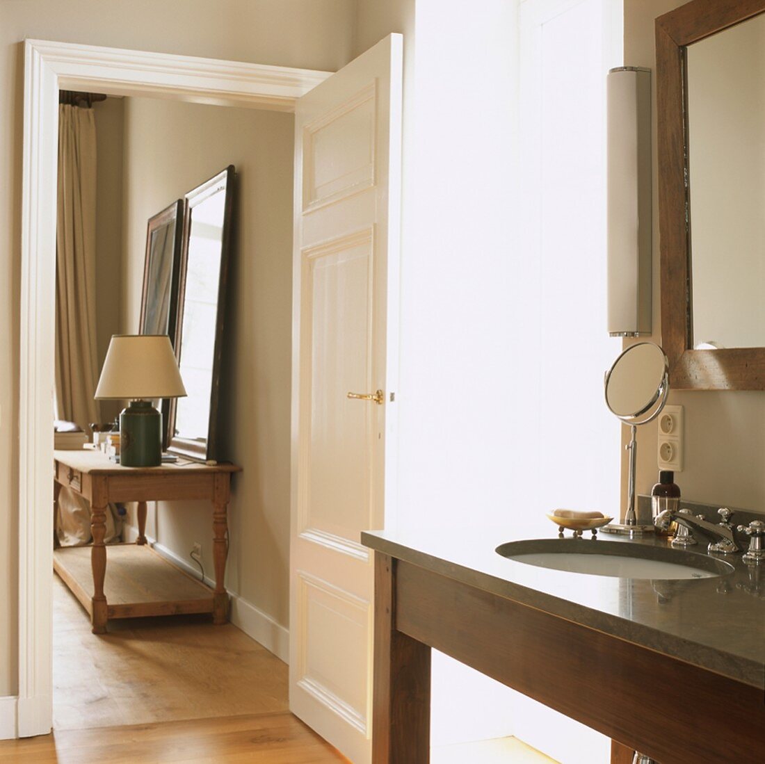 Durch die geöffnete Tür fällt der Blick vom Badezimmer in einen Nebenraum des elegant eingerichteten Wohnhauses