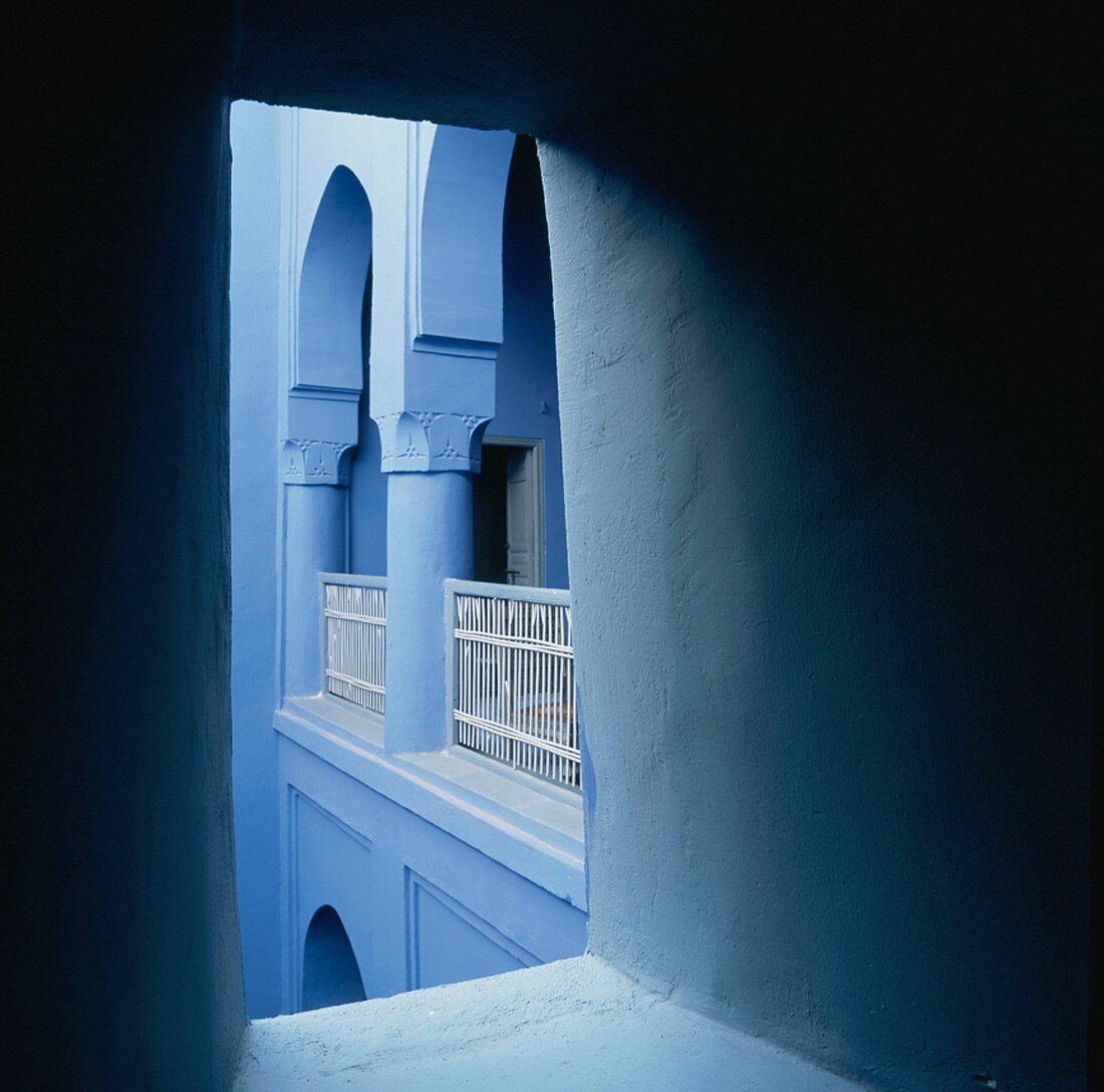 Blick durch eine Wandöffnung auf den blauen Arkadengang eines orientalischen Wohnhauses