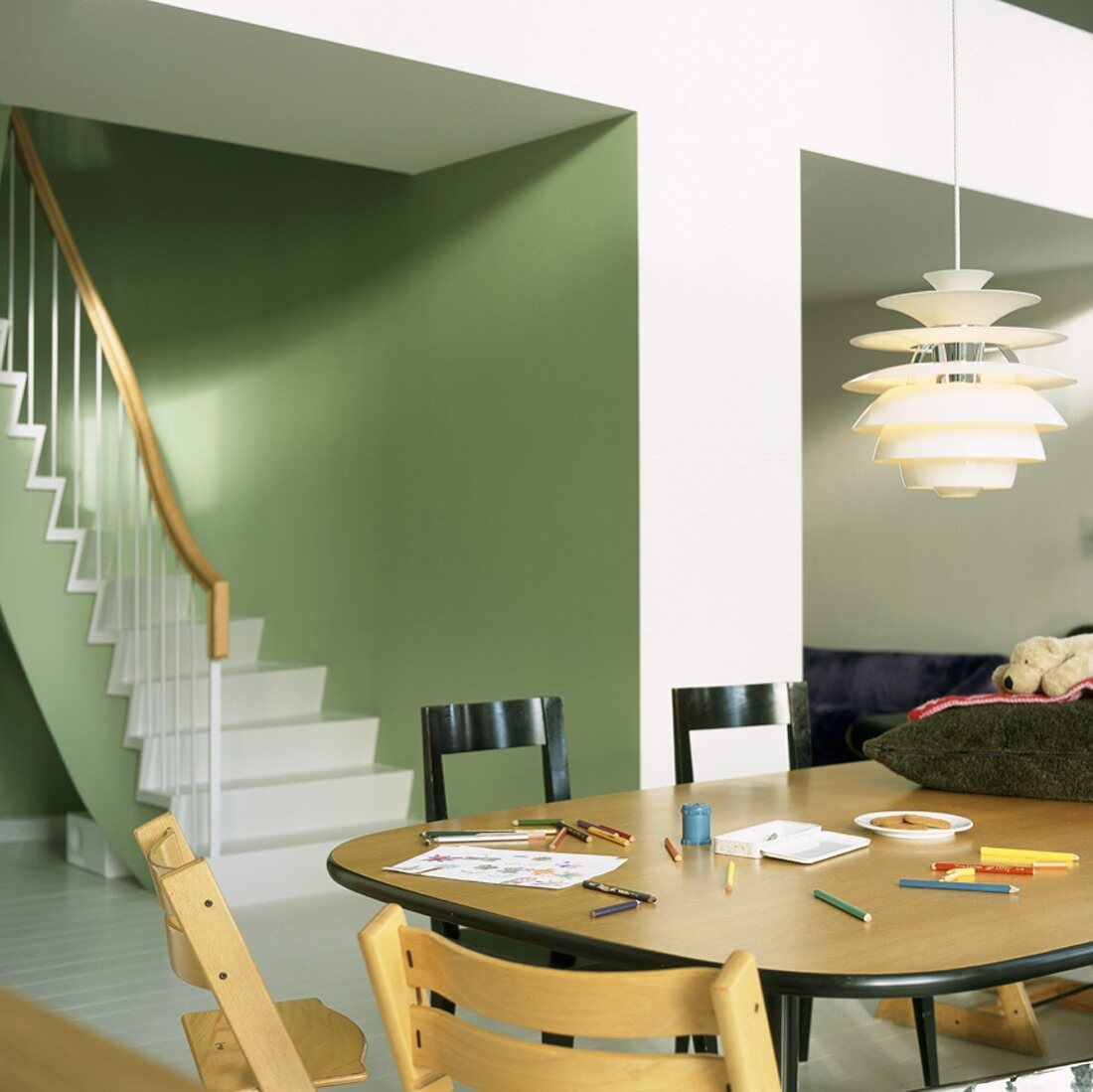 Kinderstühle und ein Vintagetisch mit Buntstiften in einem grünen Wohnraum