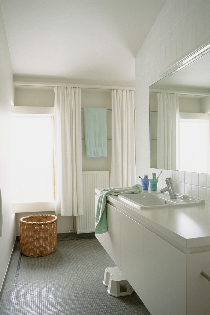 Ein schlichter, weisser Waschtisch im Badezimmer mit Mosaikfliesenboden