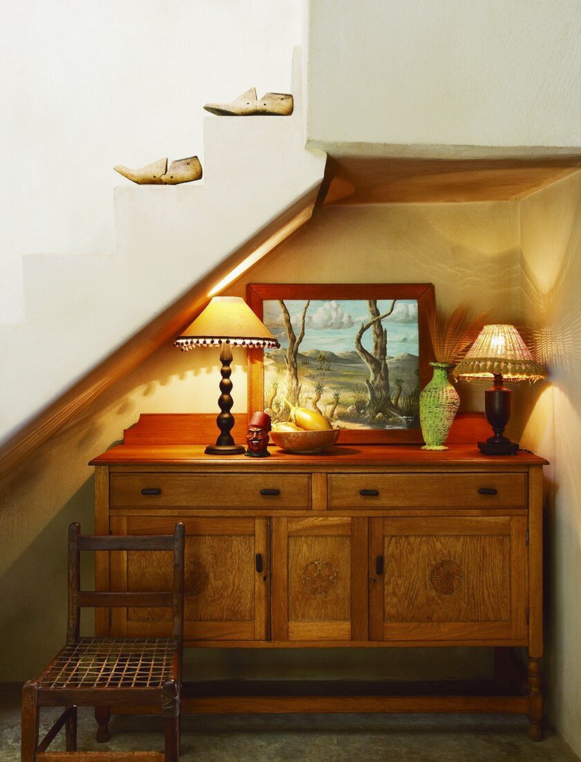 Schöne alte Holzkommode mit Dekoration in der Treppennische eines Landhauses