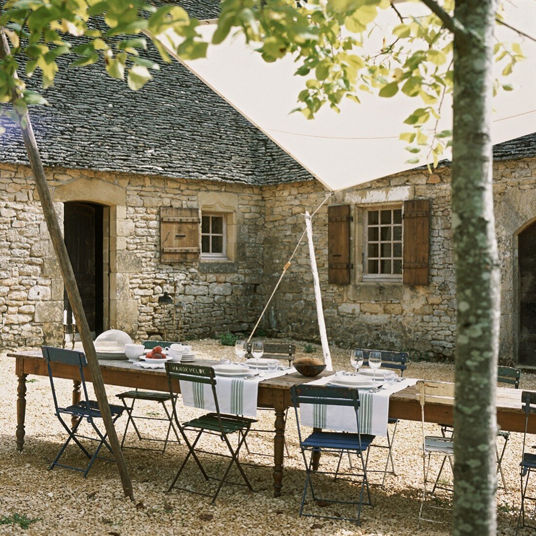 Eine lange Tafel mit Klappstühlen im Innenhof eines urigen Bauernhauses