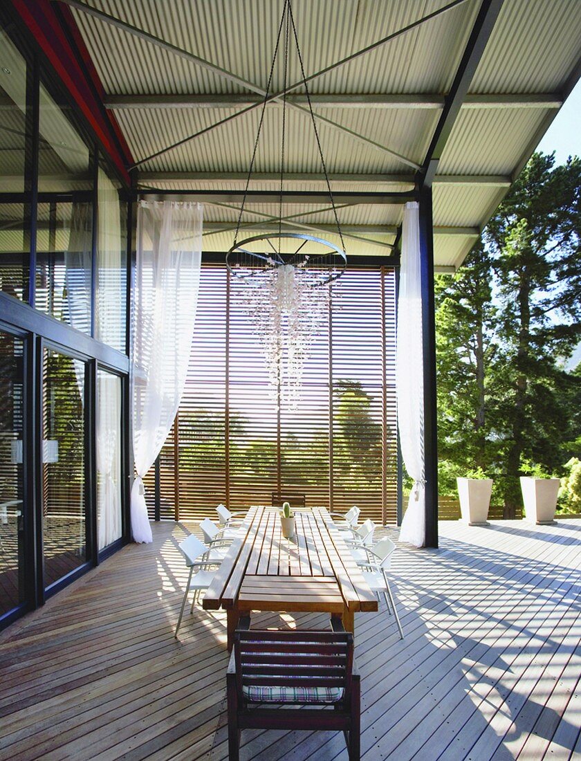 Die überdachte Terrasse des modernen Wohnhauses bietet genügend Platz für einen langen Esstisch