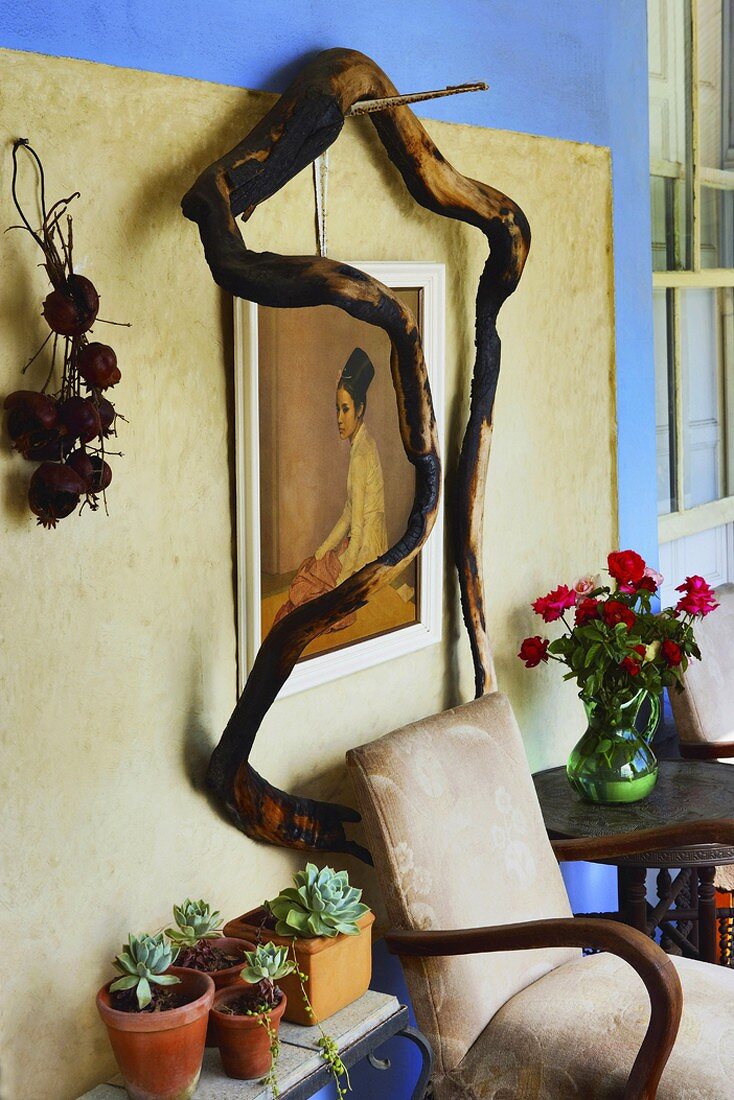 Treibholz umrahmt ein altes Gemälde, das über einem antiken Polsterstuhl hängt