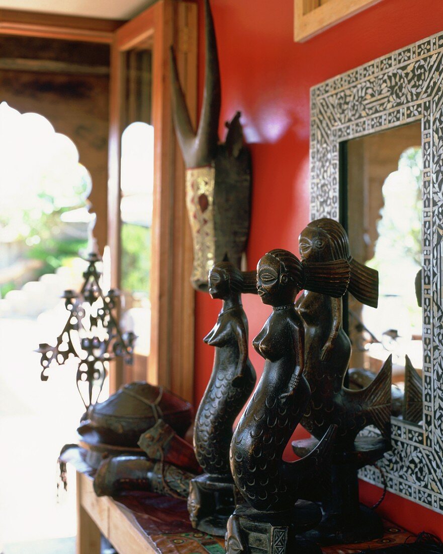 Ethnoskulpturen aus Holz vor einer roten Wand