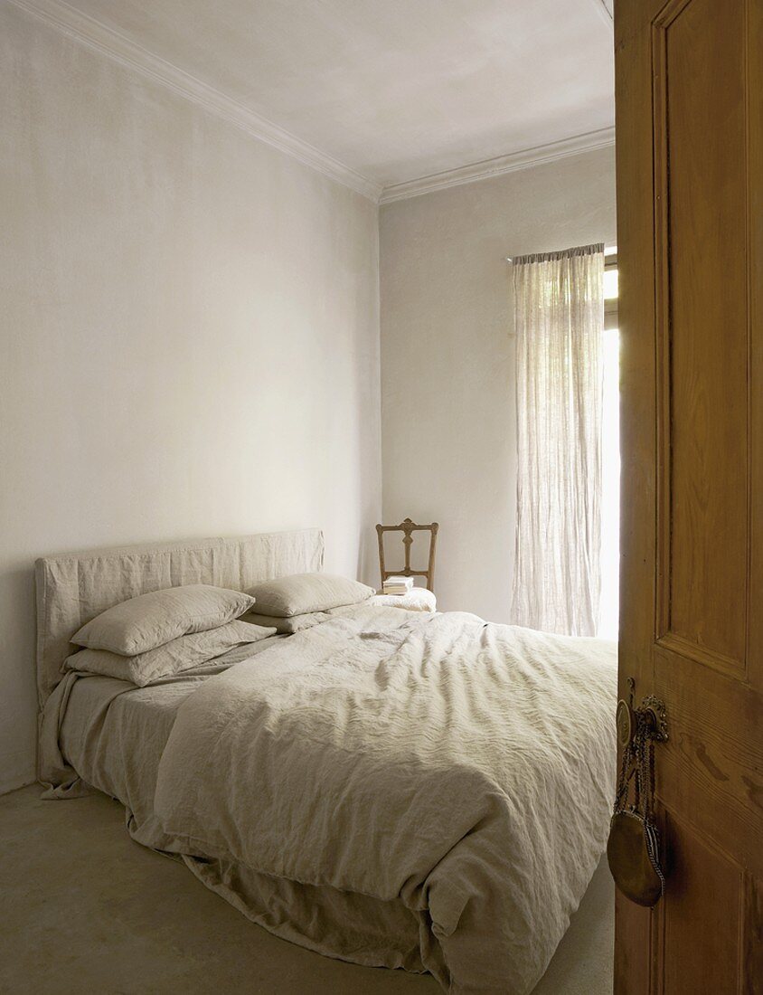 Blick durch die geöffnete Schlafzimmertür auf das gemütliche Bett mit grauer Bettwäsche