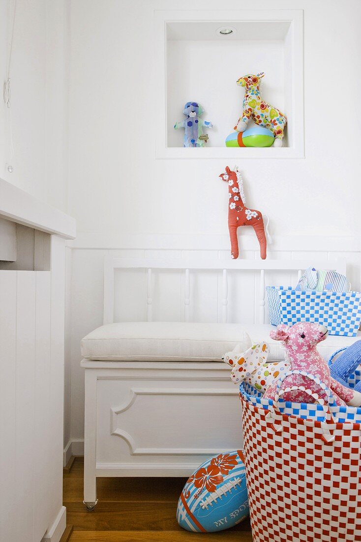 Farbenfrohes Spielzeug und weiße Sitzbank in einer Zimmerecke mit Wandnische