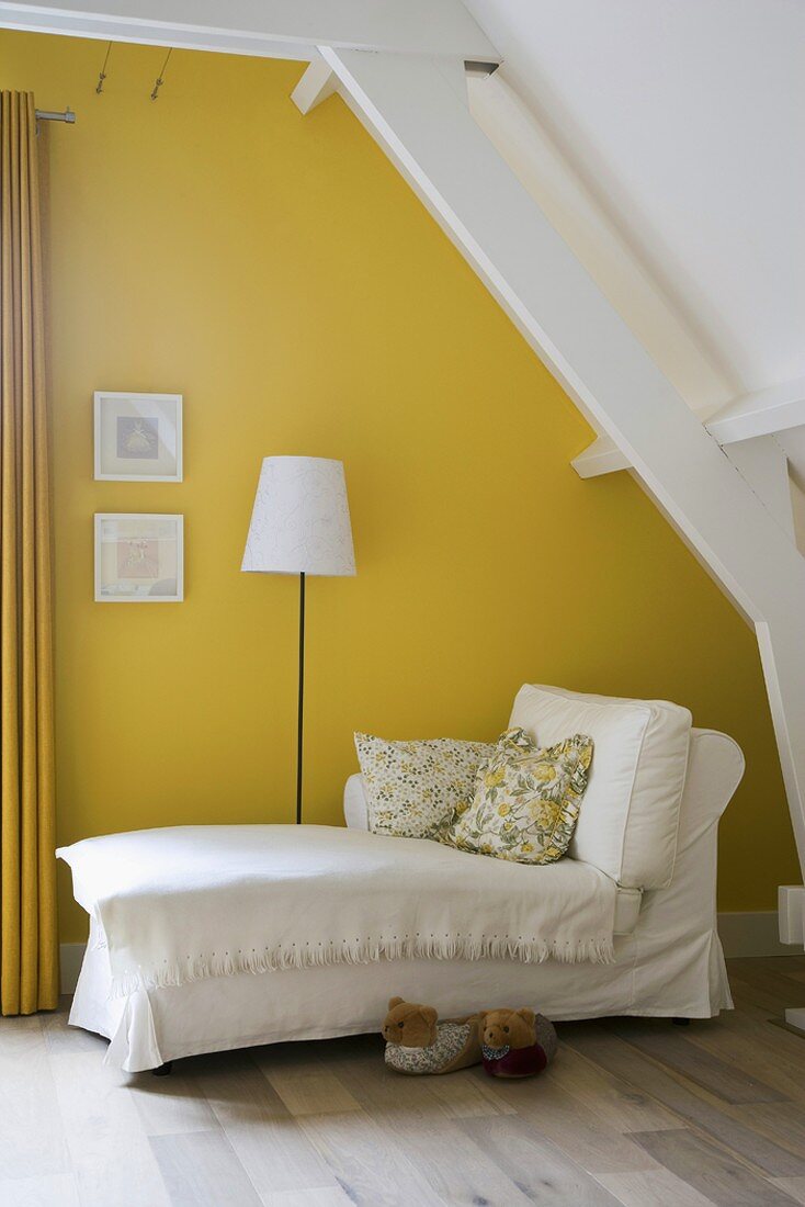 Chaise Longue mit Husse im gelben Dachgeschosszimmer mit Dielenboden