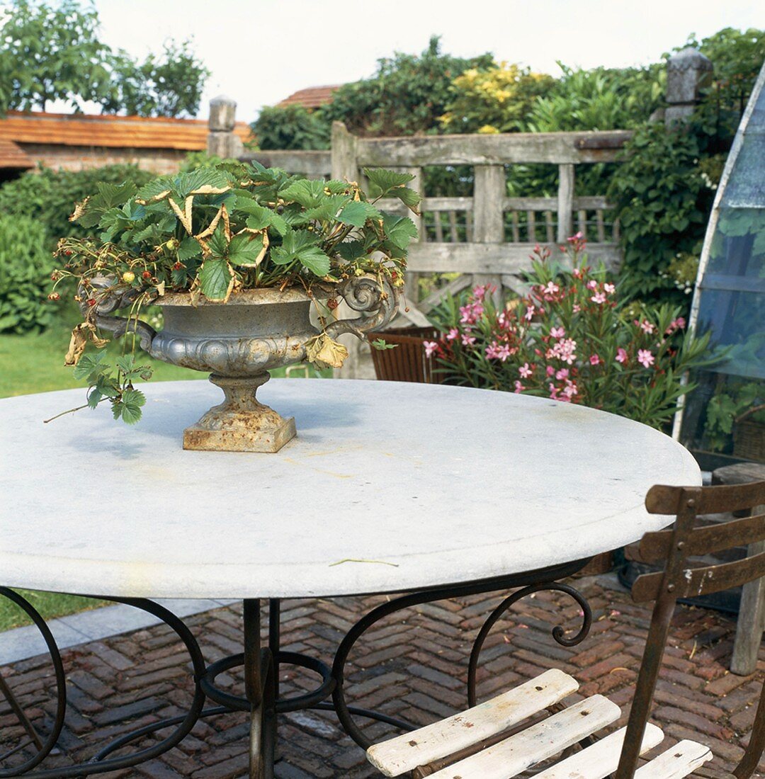 Antike Amphorenvase auf einem runden Vintage-Gartentisch auf der Terrasse