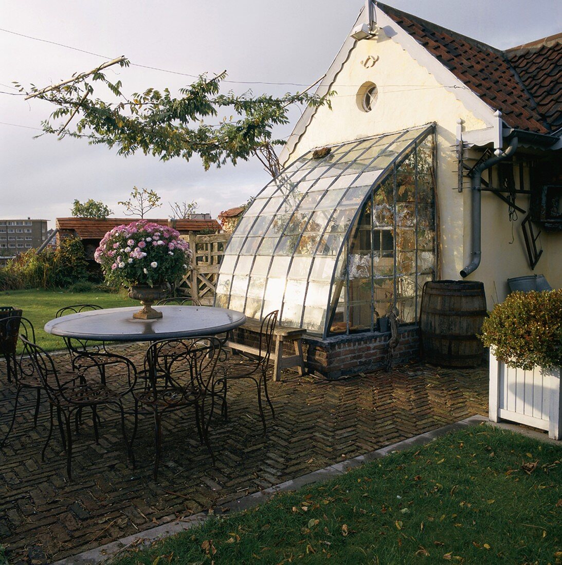 Schöne Gertentischgarnitur auf der Steinterrasse eines alten Bauernhauses mit Glasanbau