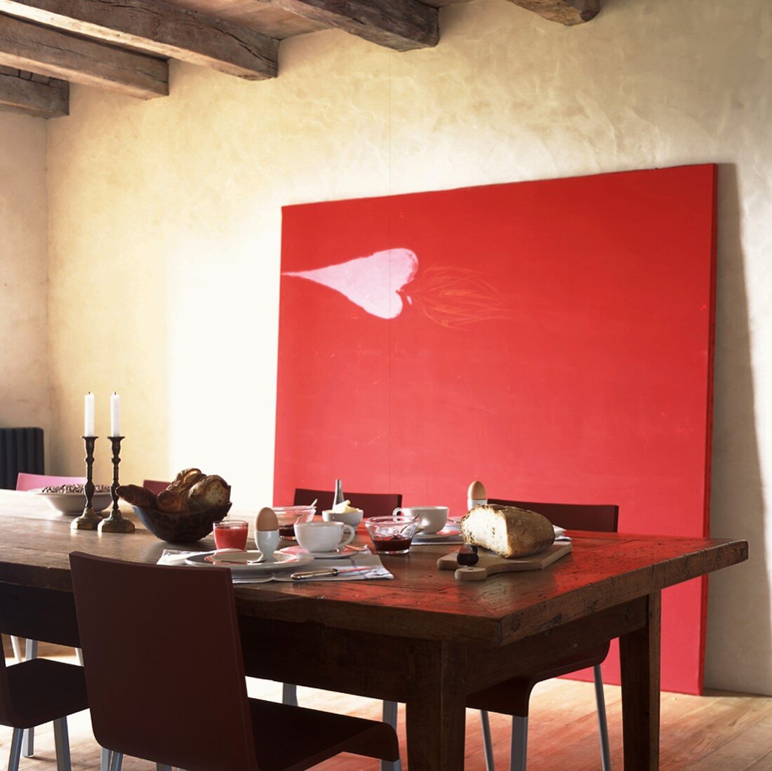 Rustikaler Frühstückstisch vor einem großen, an der Wand lehnenden Gemälde in Rot