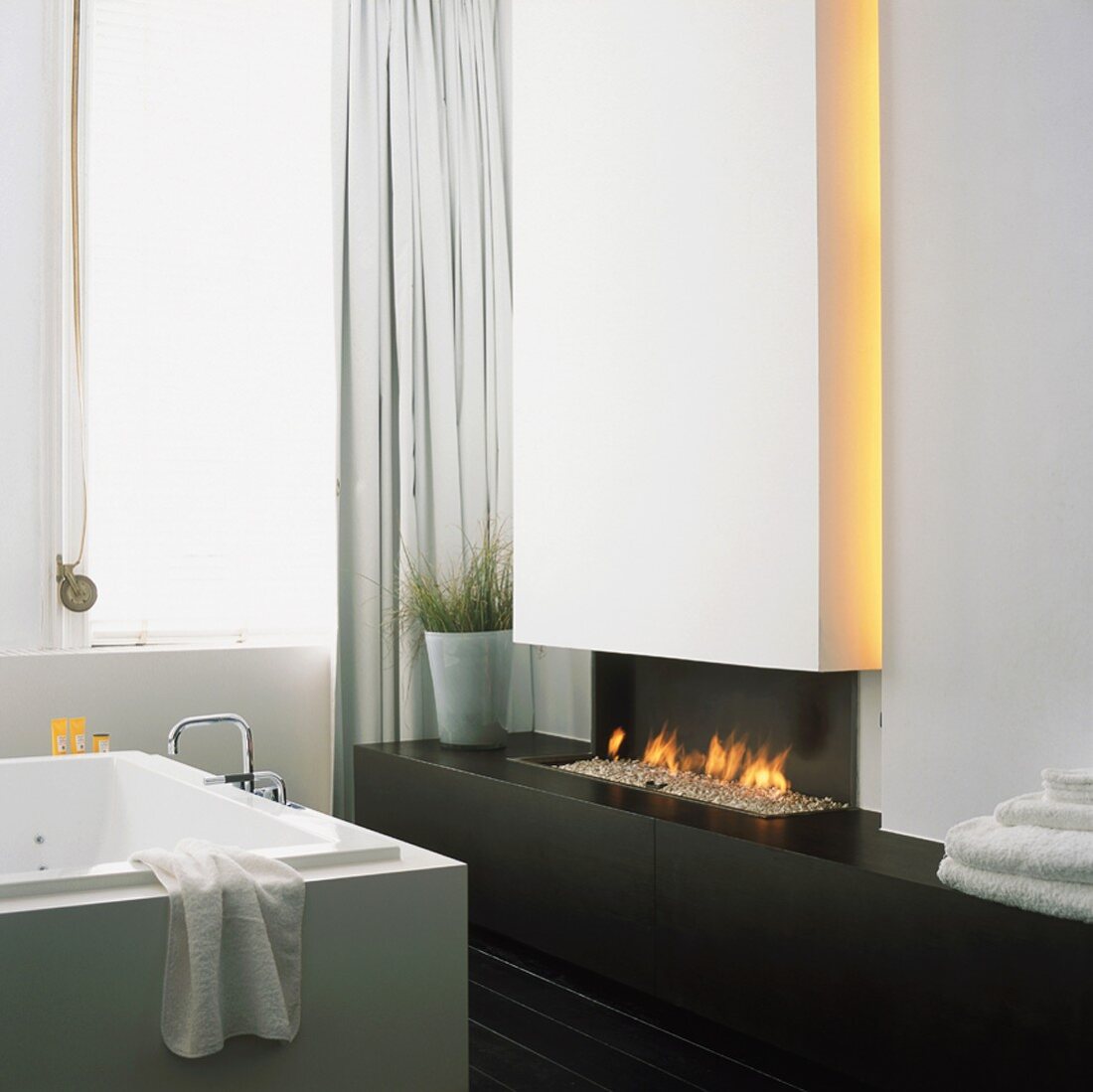 Luxuriöses Badezimmer mit minimalistischem Designerkamin und Badewanne