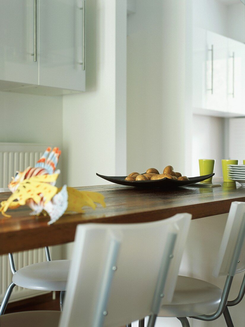 Detail einer Küchentheke mit Kunststoffstühlen und Geschirr