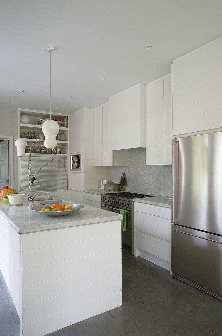 Moderne, offene Küche mit weissen Schränken, Marmorplatten und Edelstahlkühlschrank