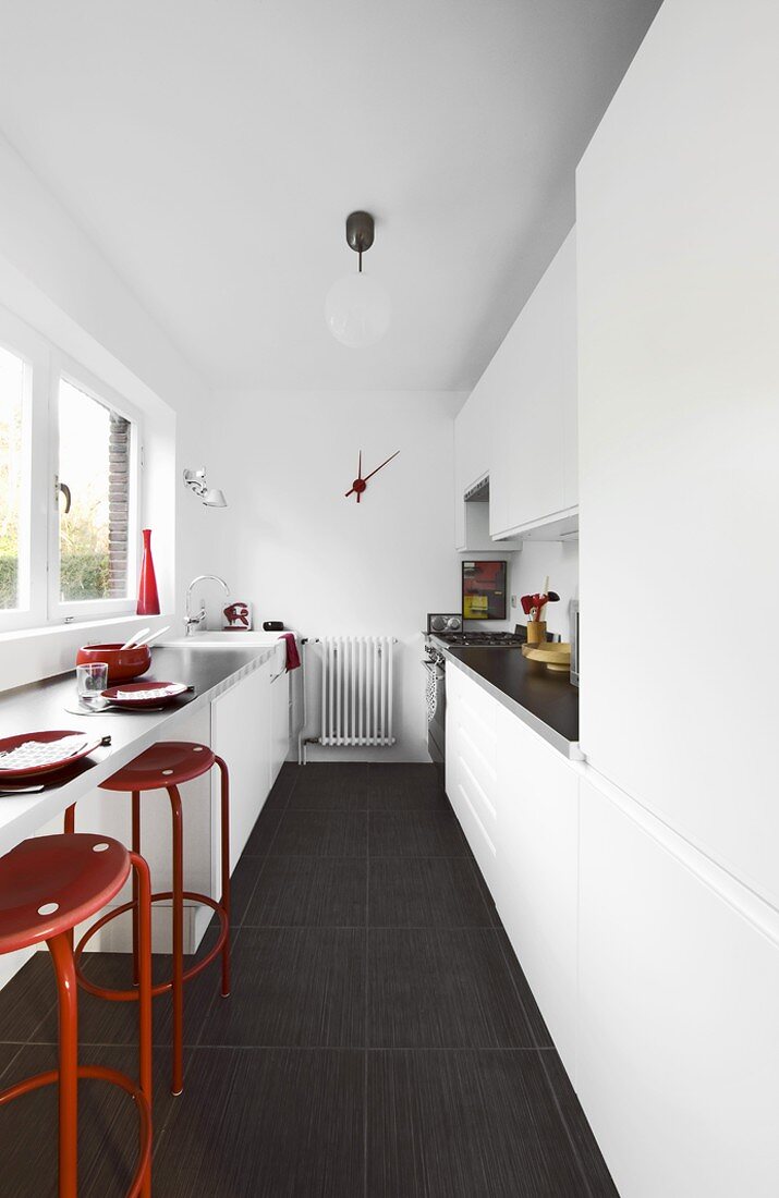 weiße, minimalistische Küche mit roten Farbakzenten