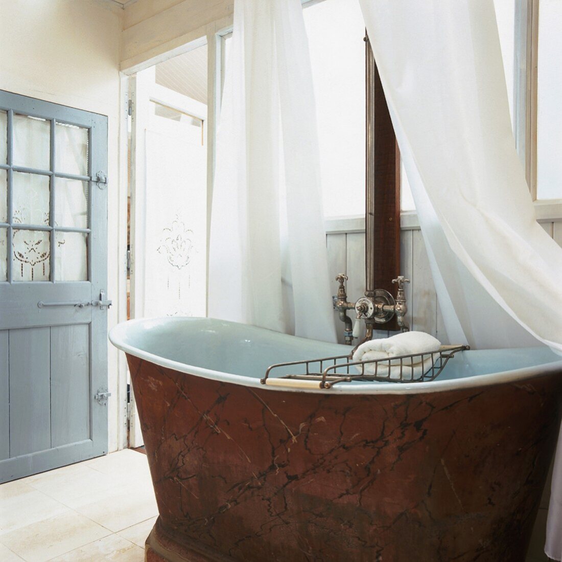 Antike Badewanne aus rotem Marmor in einem holzvertäfelten Badezimmer mit Fensterwand