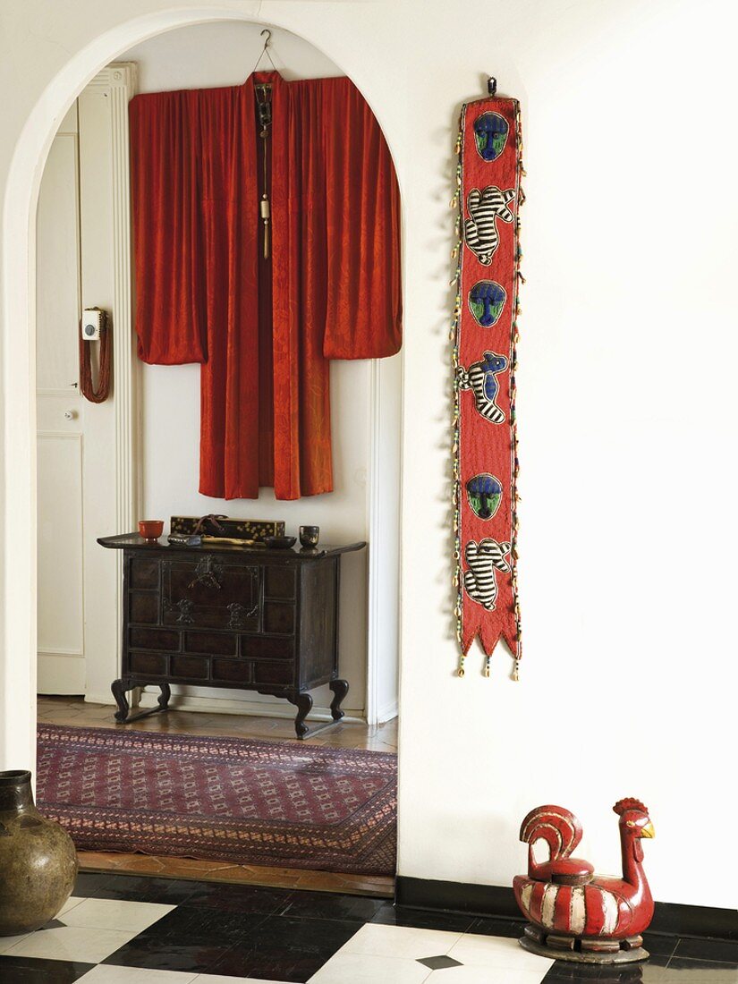 Eingangsbereich mit kleiner, chinesischer Kommode und rotem, dekorativ drappiertem Kimono